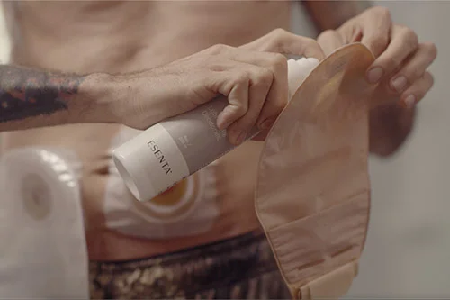 man applying a spray to an ostomy