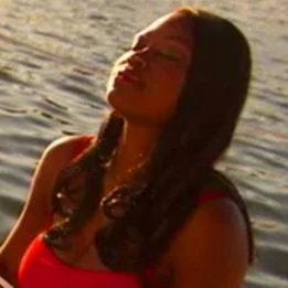 uma pessoa com uma camisa vermelha e uma camisa vermelha com um corpo de água atrás do