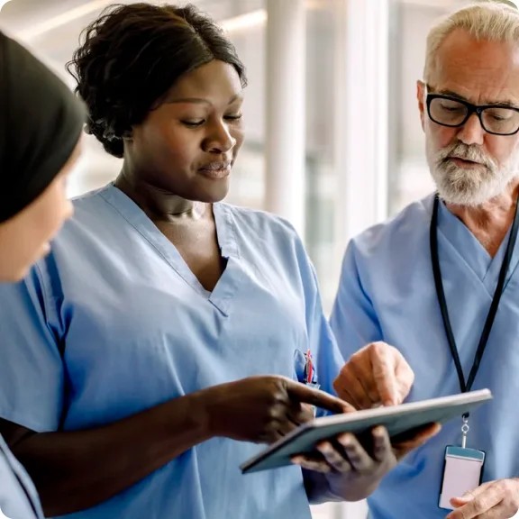 세 명의 의료 전문가가 태블릿을 보고 토론하고 있습니다.