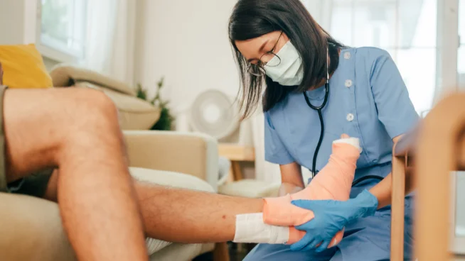 Wundexpertin verbindet den Fuß eines Patienten mit einem Wundverband