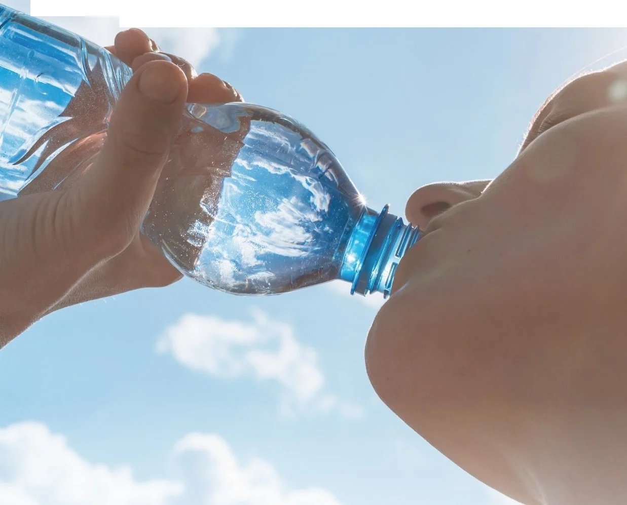 un paio di mani che tengono una bottiglia d'acqua trasparente